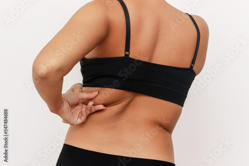 Foto Cropped shot of a young tanned woman with waist flabs holding fat folds on her back isolated on a white background