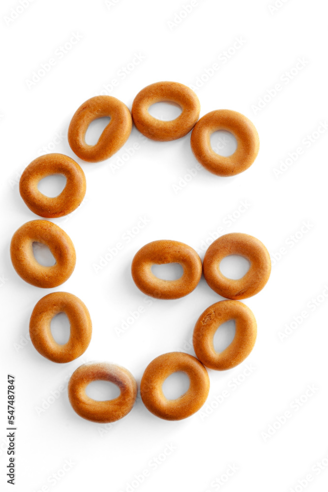 Letter G bagel. Bagels font. Alphabet from set of small dry bagels isolated on white background. ABC symbols. Letter G bagel. Bagels font. Alphabet from set of small dry bagels isolated on white background. ABC symbols.