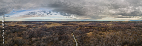 Panorama of a dry marsh land setting with a wooden boardwalk under a sky with interesting white and gray clouds.  © Craig Taylor Photo
