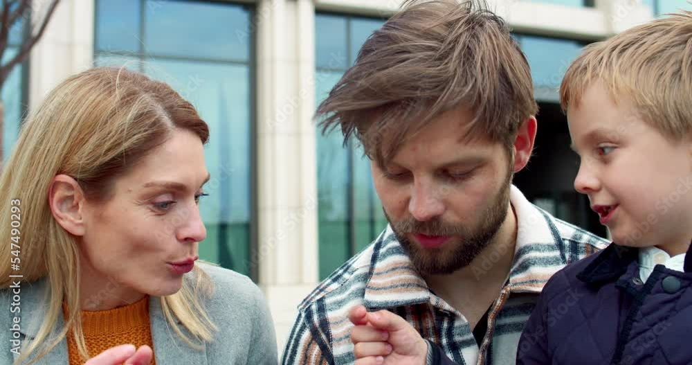 Close-up portrait of little happy playful adorable boy spending time having fun with parent talking smiling. Young blonde loving mom speaking with cheerful kid and handsome dad outside.
