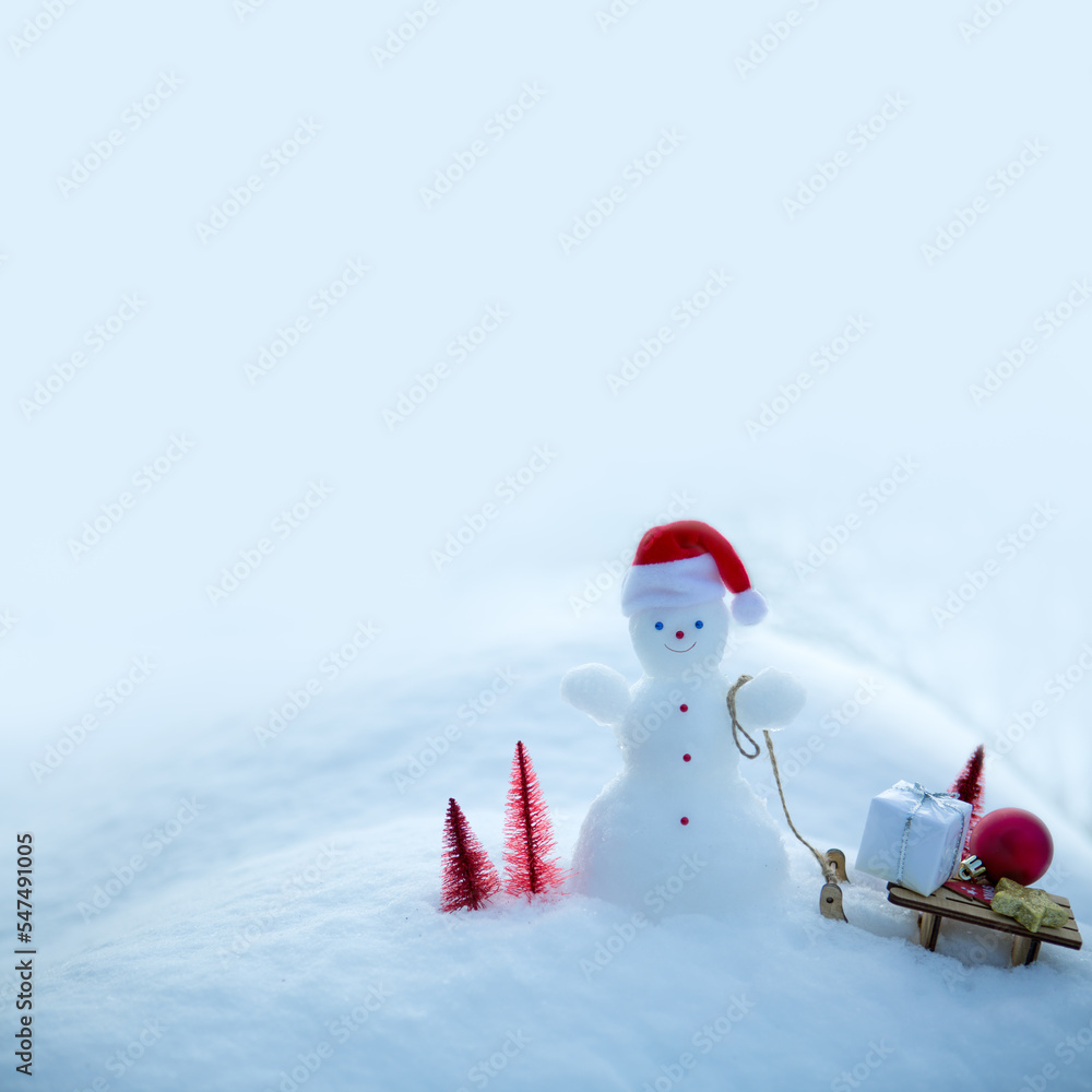 Christmas snowman with red hat and gifts stand in white snow.