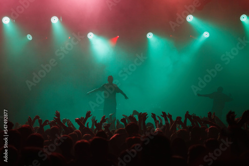 Rap singer performing on concert in music hall. Silhouette of rapper singing on stage in night club