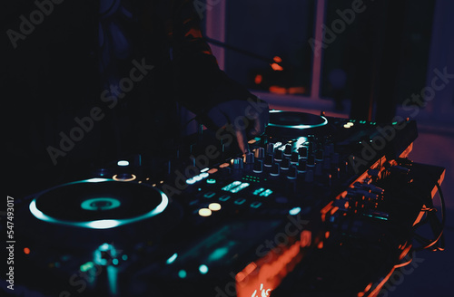 Dj plays music set on rave party in night club. Disc jockey playing musical tracks with sound mixer and turntables on concert stage.