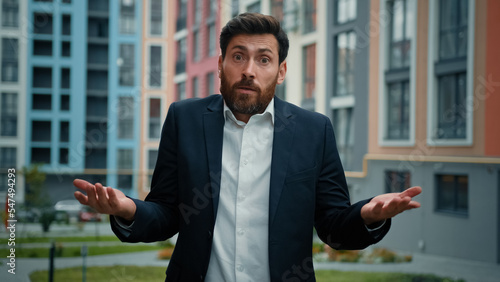 Doubtful sad frustrated businessman bearded man shrugging shoulders don't know answer incertitude gesture uncertain reaction on difficult question confused caucasian guy millennial feel disappointment photo