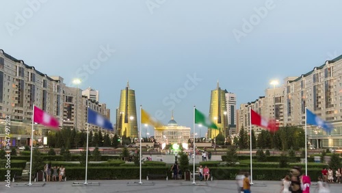 A square with flags in front of Ak Orda with Altyn Orda business center in the foreground timelapse. Ak Orda is the presidential residence in Astana, the capital of Kazakhstan. Nur-Sultan city at photo