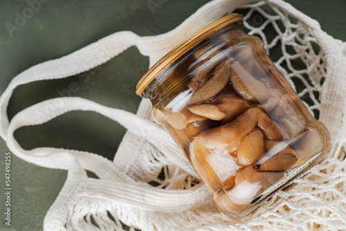Fototapeta Naklejka Na Ścianę i Meble -  Jar of pickled mushrooms in a mesh bag. Zero waste concept with canned mushrooms and string bag. Top view