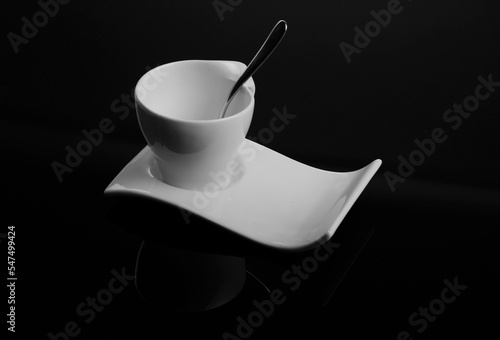 white cup on isolated black background, biała filiżanka na falistym spodku, porcelanowa filiżanka na czarnym tle, biała filiżanka, filiżanka z łayżeczką, falisty spodek, czerń i biel, czarne tło