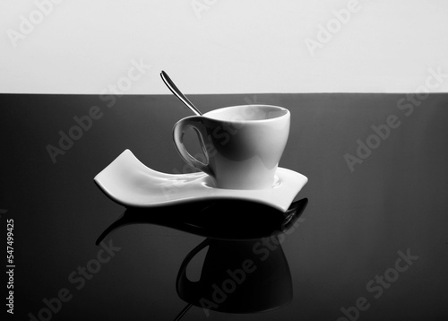 white cup on isolated black background, biała filiżanka na profilowanym, falistym spodku, biała porcelanowa filiżanka na szarym tle, nowoczesna biała filiżanka, filiżanka z łayżeczką, falisty spodek photo