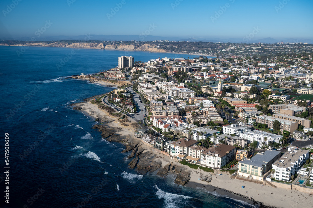 Aerial image of Children's Pool by Seal Rock in La Jolla San Diego California with mountains in the background and palm tree lined roads