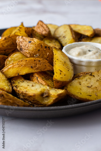 Oven roasted potatoes with skins, sliced, with sauces close-up