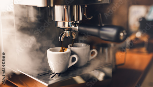 Foto Portafilter machine pours fresh coffee into espresso cups