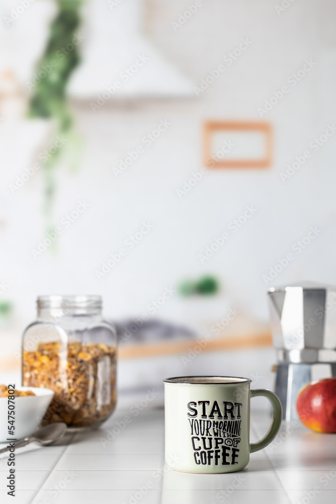 Mug of morning coffee on white tile tabletop in kitchen. Healthy breakfast consept with coffee, oats and apple. Domestic life. Text space Mug of morning coffee on white tile tabletop in kitchen. Healthy breakfast consept with coffee, oats and apple. Domestic life. Text space