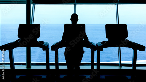 Youth working out on a treadmill in a gym on a cruise ship while looking at the ocean