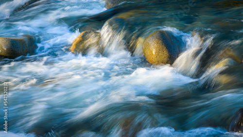 Картината върху платно Mountain stream rushes over smooth river rocks with streaks of water against the