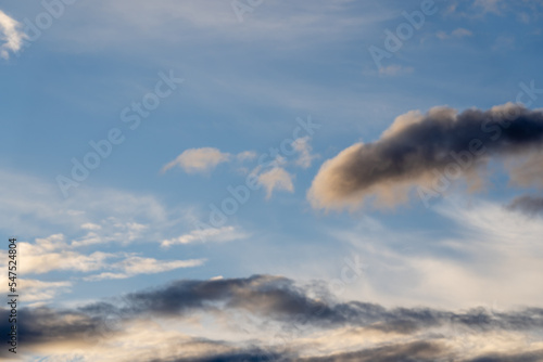 Bright blue cool autumn sky with light airy transparent clouds where some dark dramatic clouds create an eerie landscape