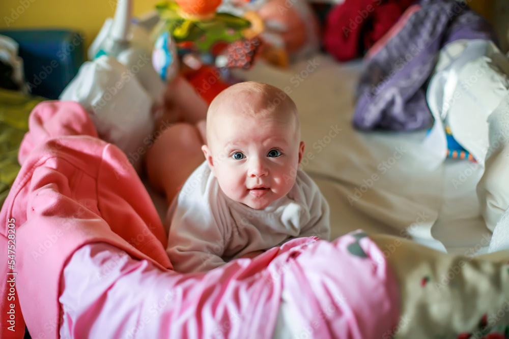 Cute little girl peeks out of the crib. The sides of the crib are hung