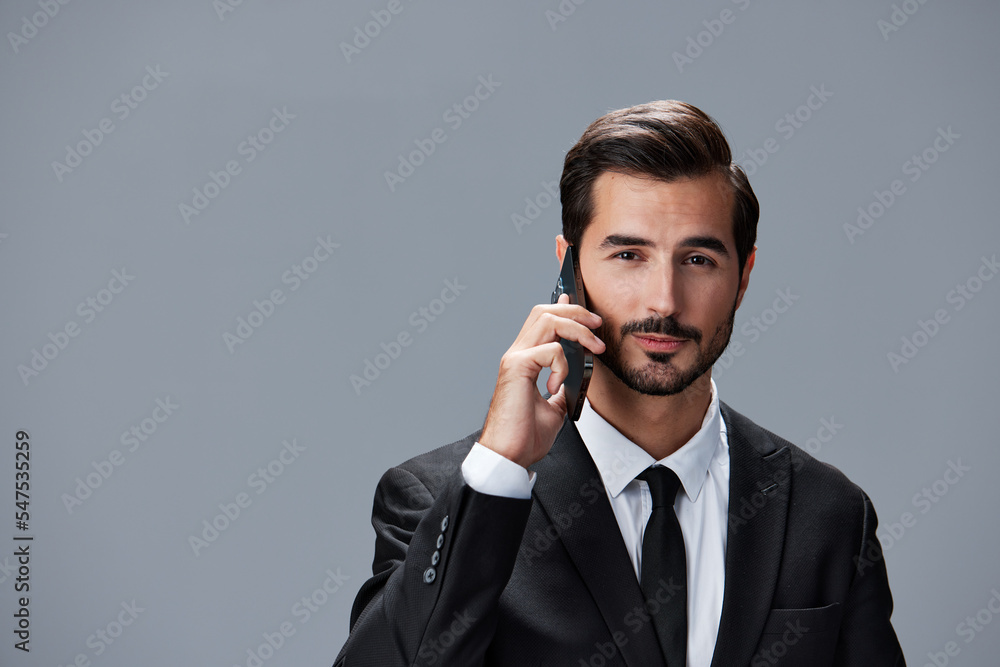 Portrait of business man with phone conversation on gray background in business suit. Business portrait of a stylish man copy space
