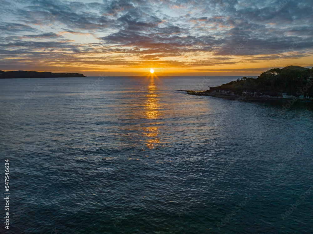 Aerial sunrise seascape with calm seas and a mix of low and medium clouds