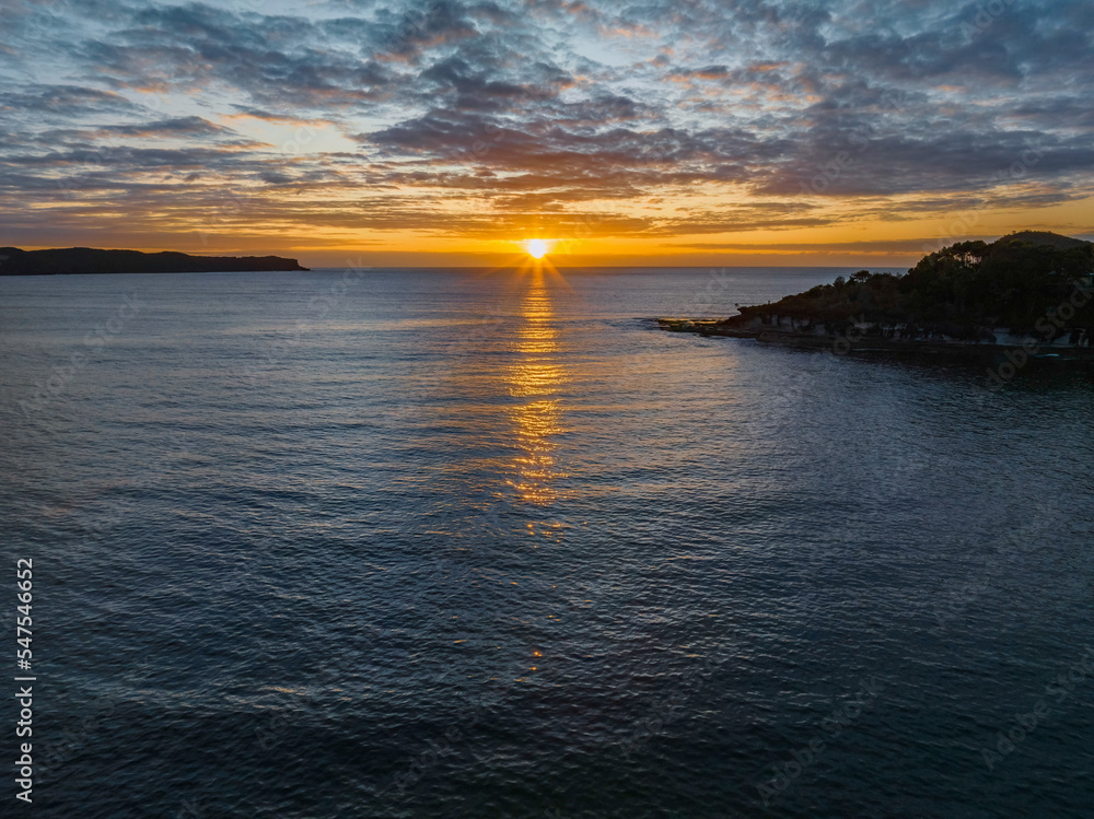 Aerial sunrise seascape with calm seas and a mix of low and medium clouds