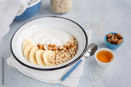 Domowe, zdrowe śniadanie. Jogurt naturalny z płatkami owsianymi, bananem i migdałami.