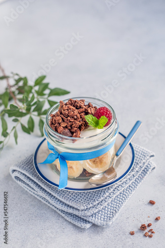 Domowe, zdrowe śniadanie. Naturalny grecki jogurt z czekoladowym musli, bananami i malinami.