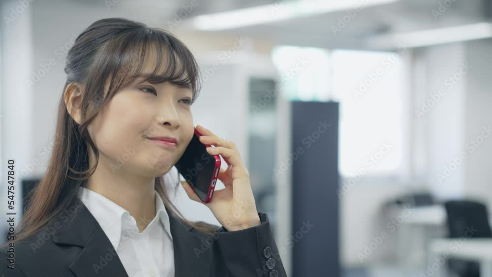 オフィスでスマホ通話するビジネスウーマン