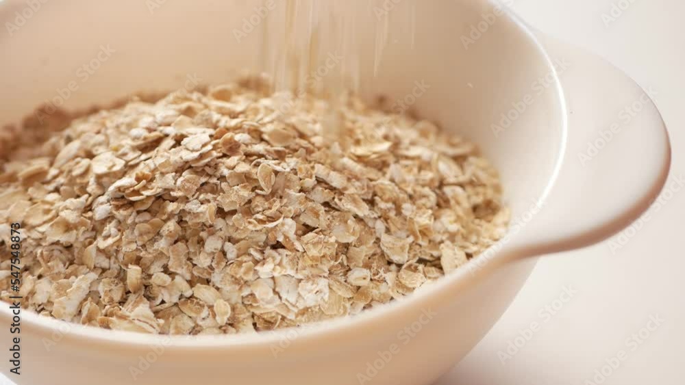 Filling dry flakes in a bowl for brewing oatmeal before breakfast. Filling dry flakes in a bowl for brewing oatmeal before breakfast.