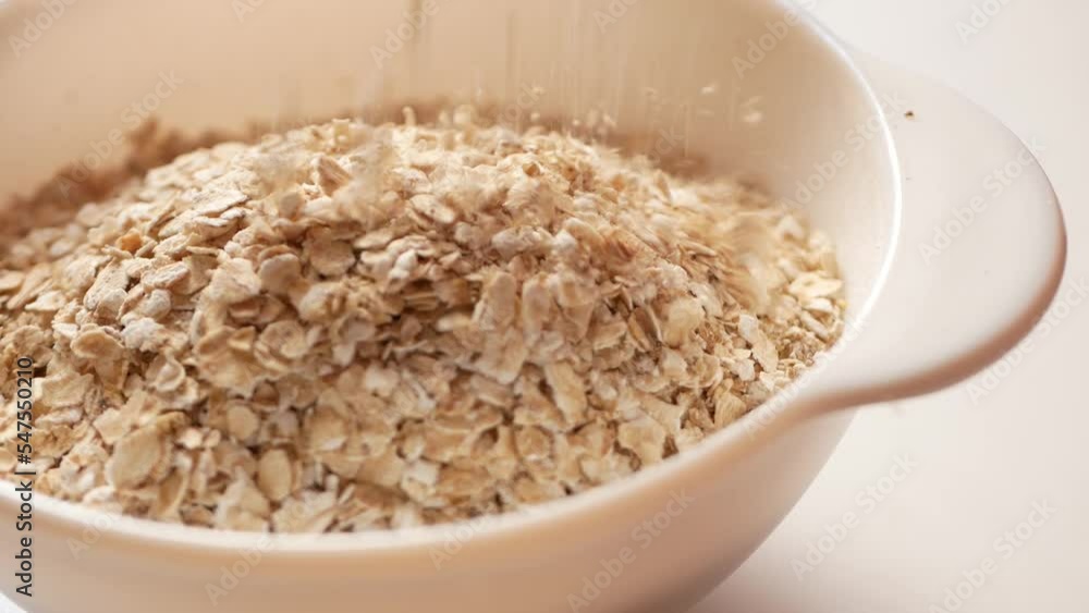 Oatmeal flakes quickly fall into the porridge brewing container. Oatmeal flakes quickly fall into the porridge brewing container.