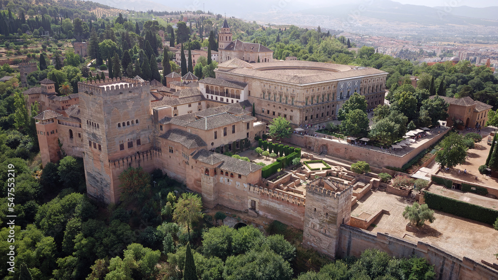 Aerial drone view of the Alhambra Palace, Granada during sunny day. Moorish Architecture. Unesco World Heritage Spain. Travel in time and discover history. Amazing destinations for holidays. 