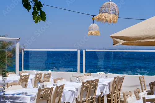 Empty tables and chairs of stylish restaurant overlooking the sea with horison.