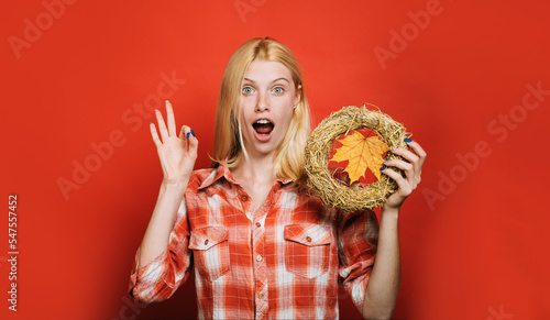 Surprised woman in plaid shirt with decorative autumn wreath showing ok sign. Handmade decoration.