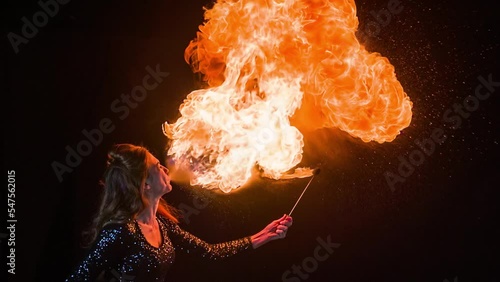 Woman fire breather blowing a fireball in slow motion.