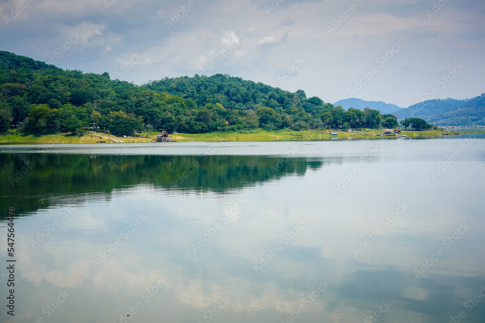 View of the jatiluhur reservoir with a wide expanse of water and full of green forest mountains in Purwakarta Regency, West Java, Indonesia
