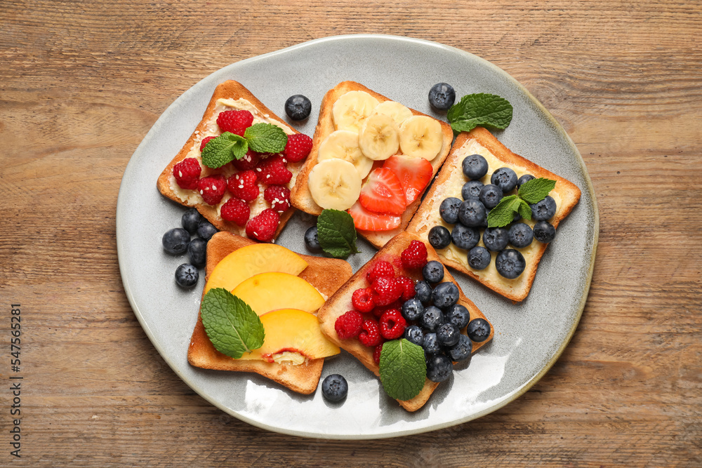 Tasty toasts with different spreads and fruits on wooden table, top view