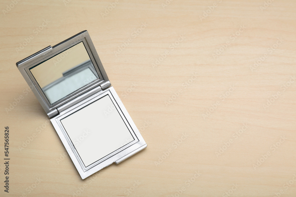Stylish cosmetic pocket mirror on wooden table, top view. Space for text Stylish cosmetic pocket mirror on wooden table, top view. Space for text
