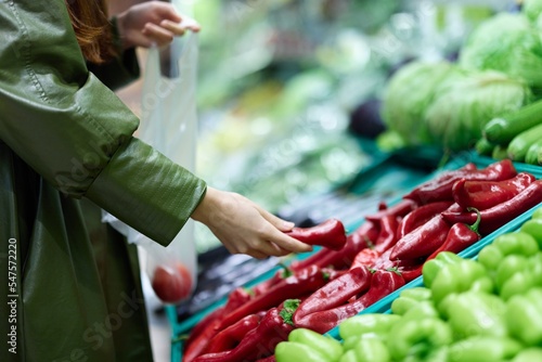 Woman at the grocery store picking fresh vegetables to cook for dinner, shopping 
