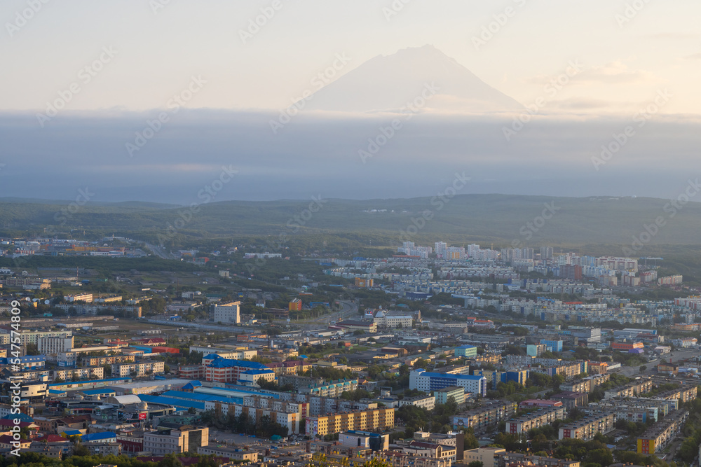 Morning cityscape. Top view of the buildings and streets of the city. Residential urban areas at sunrise. Koryaksky volcano in the distance. Petropavlovsk-Kamchatsky, Kamchatka Krai, Russian Far East.