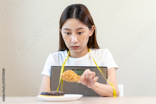 Canvas Print Diet, attractive asian young woman, girl restrained to eat doughnut, bakery and fried chicken, fast food to lose, loss weight, hugging weight scales on table at home