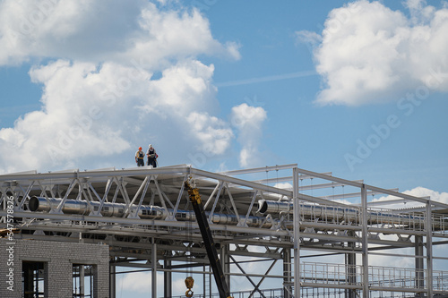 Construction frame roof building. A construction manager and a worker are discussing a roof construction plan.