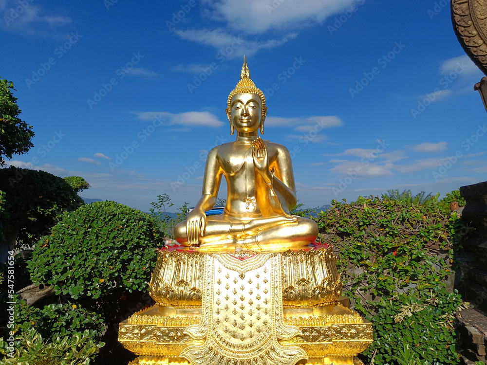 Obraz premium Beautiful Golden Buddha statue against blue sky and clouds in Thailand temple, Wat Phra That Phasornkaew Khao Kho District, Phetchabun province