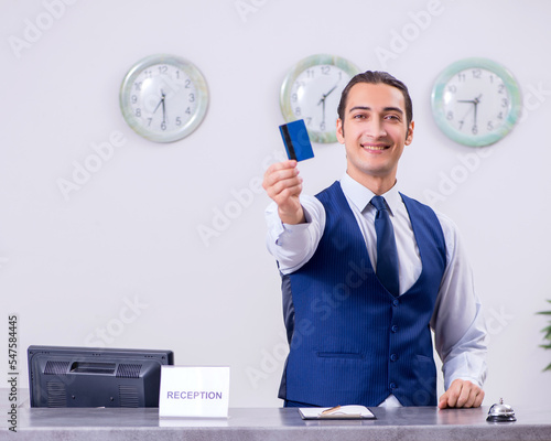 Young man receptionist at the hotel counter