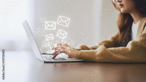 Email marketing and newsletter concept. Woman using computer laptop and sending online message with email icon photo