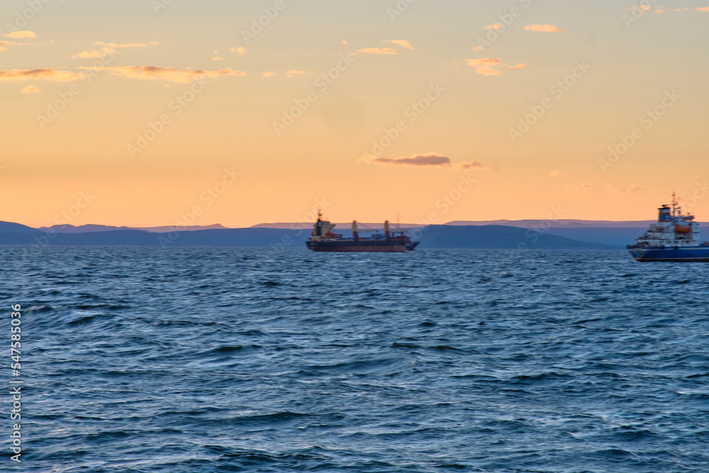 Fishing ships are in the roadstead at sunset.