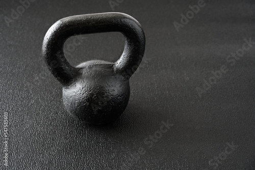 Simple fitness, black iron kettlebell on a black gym floor 