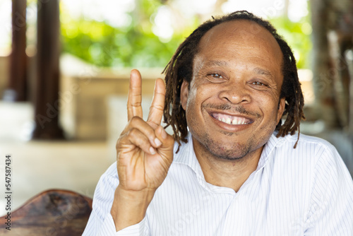 Happy smiling African man pointing up 2 fingers, v for victory gesture photo