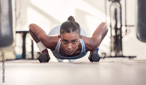 Dumbbell, fitness and black woman training, workout or bodybuilder in gym floor portrait for body goals, muscle and wellness motivation. Strong, power and sports girl doing push up exercise with gear