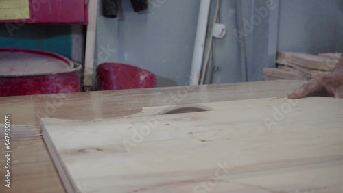 Factory worker cuts a tree with a circular saw. Sawdust of plywood is flying