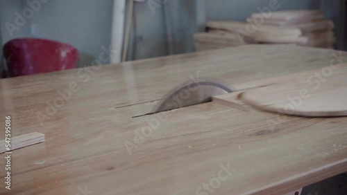 Factory worker cuts a tree with a circular saw. Sawdust of plywood is flying