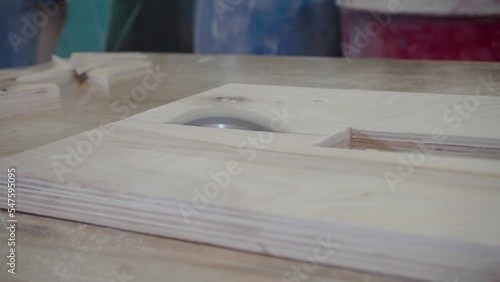 Factory worker cuts a tree with a circular saw. Sawdust of plywood is flying