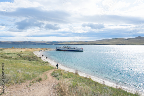 Large pleasure boat with tourists disembarking to the shore. Baikal lake